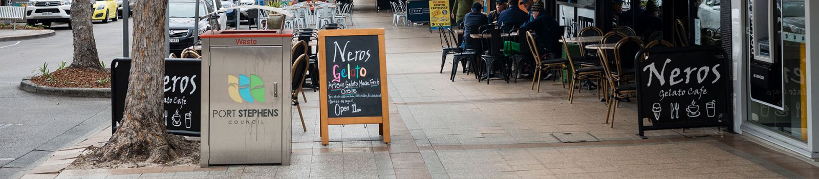 Image of an advertising banner on the pavement with people walking past banner image