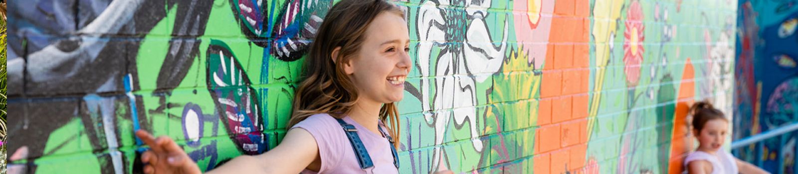 Image of a kid standing in front of a wall and smiling  banner image