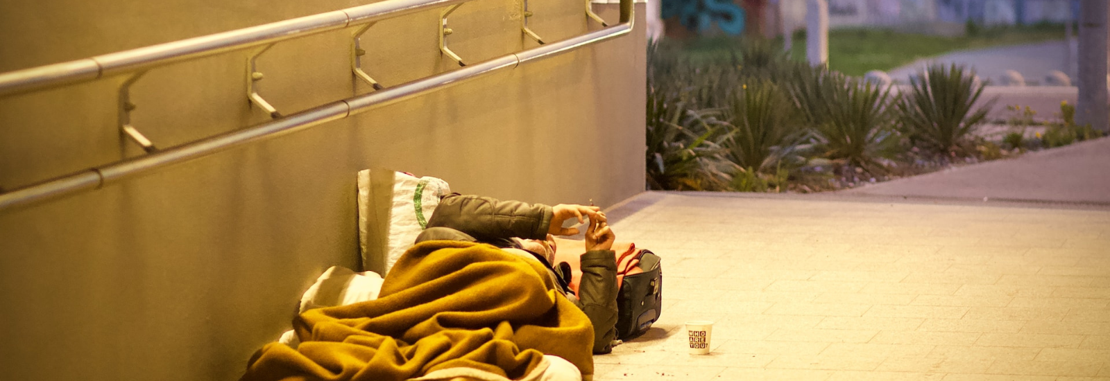 Homeless person asleep at train station banner image
