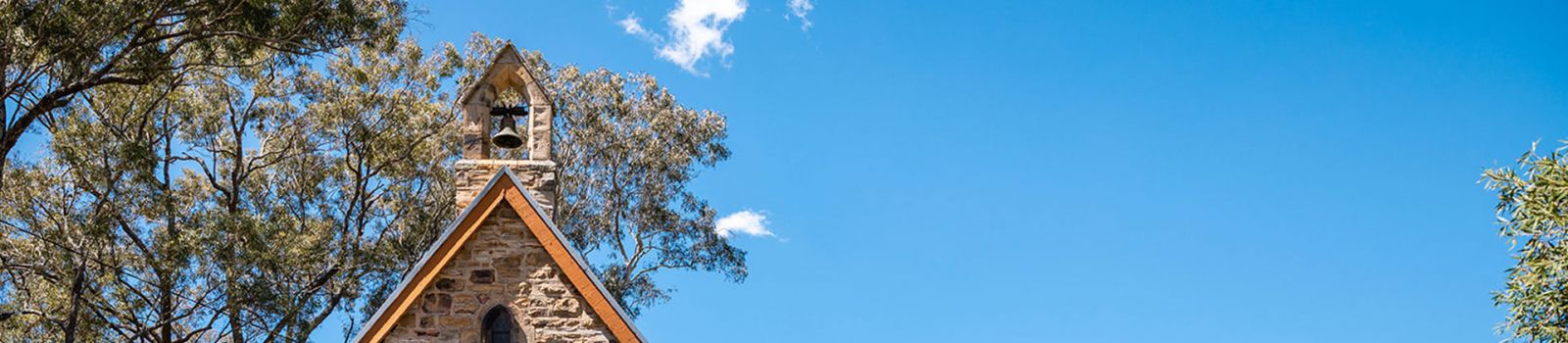 Image of the top of an old church against a blue sky banner image