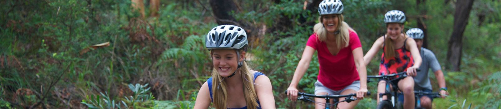 Image of girls cycling through a forest banner image