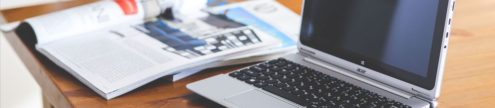 Image of a computer with a magazine next to it banner image