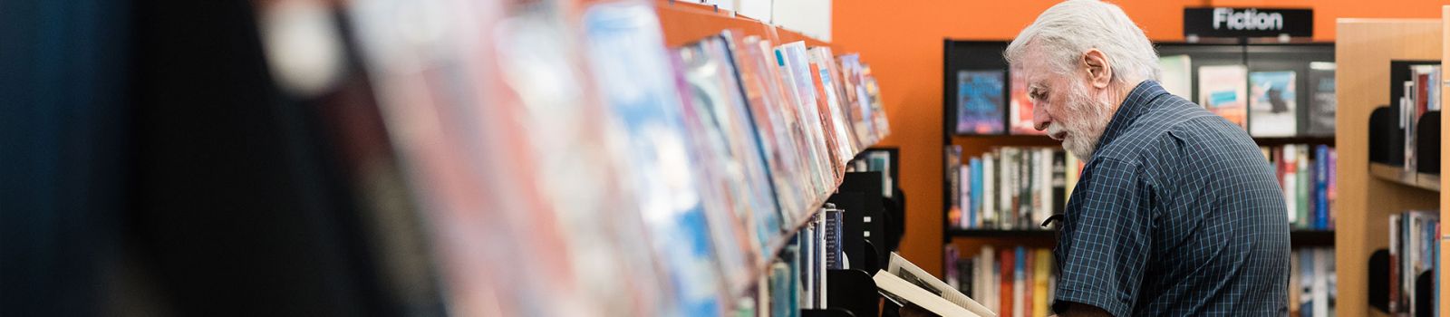 A man looking at a row of books in our library banner image