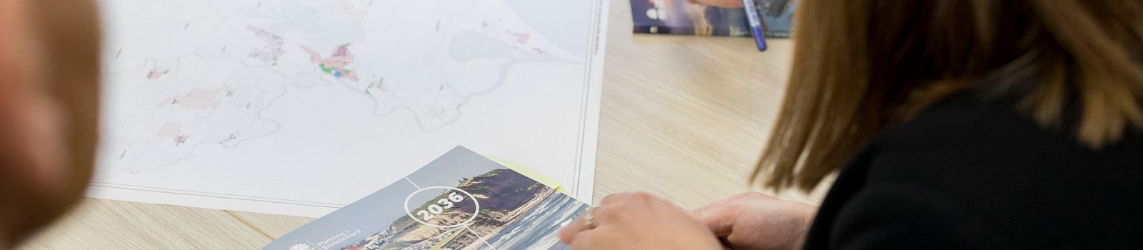 Picture of a group of people looking over paper documents  banner image