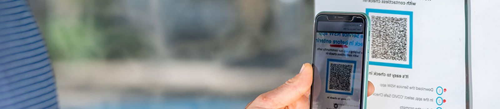 Image of someone holding up their phone with a QR code to 