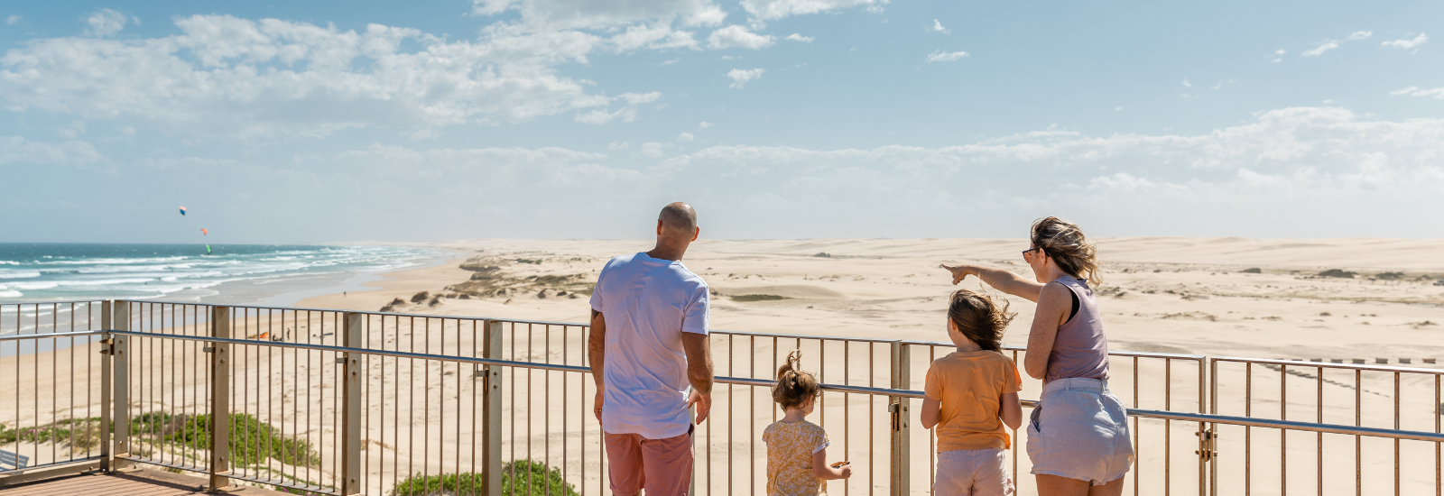 Family looking out from a bridge into the sea banner image