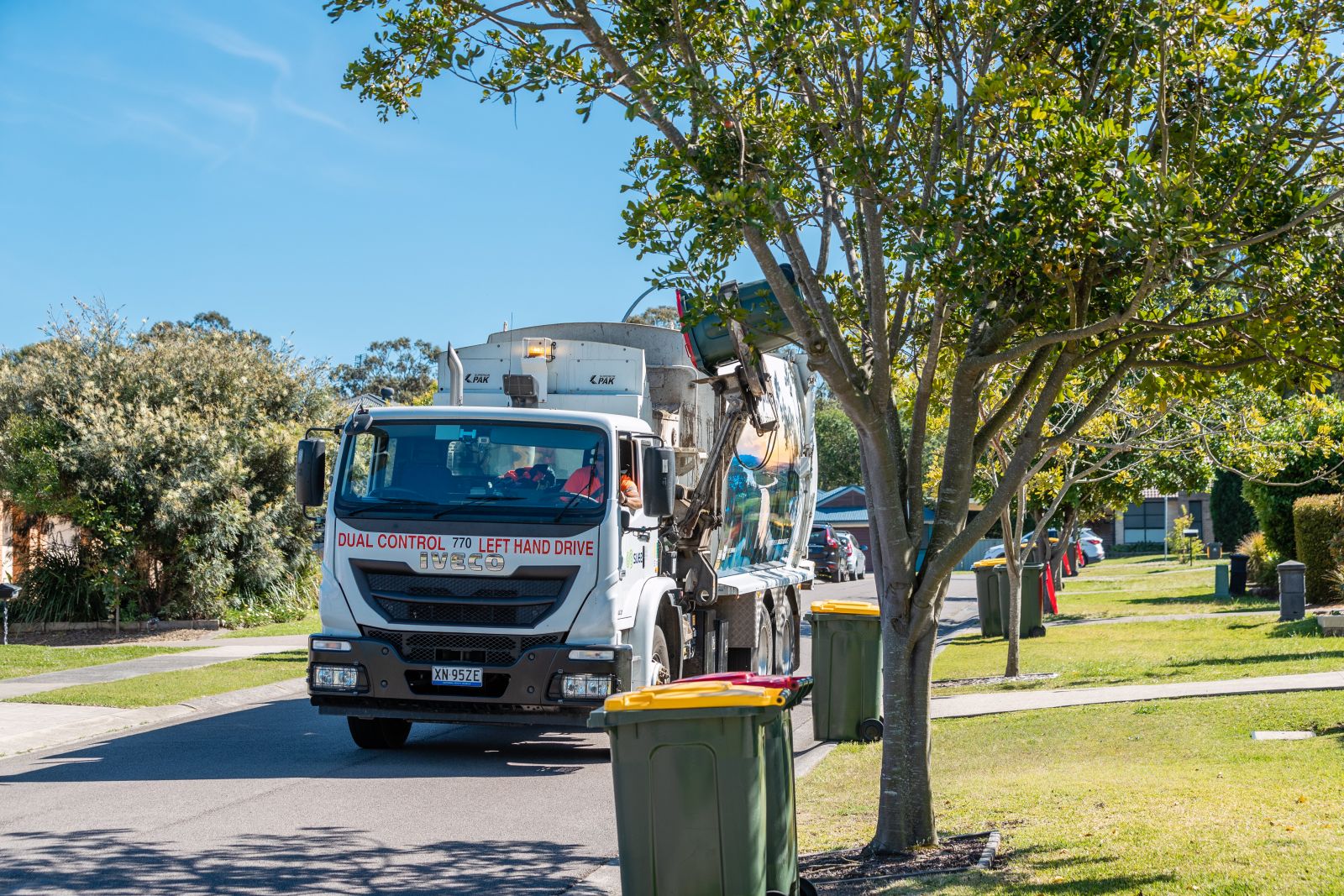 Garbage truck picking up yellow lid bins banner image