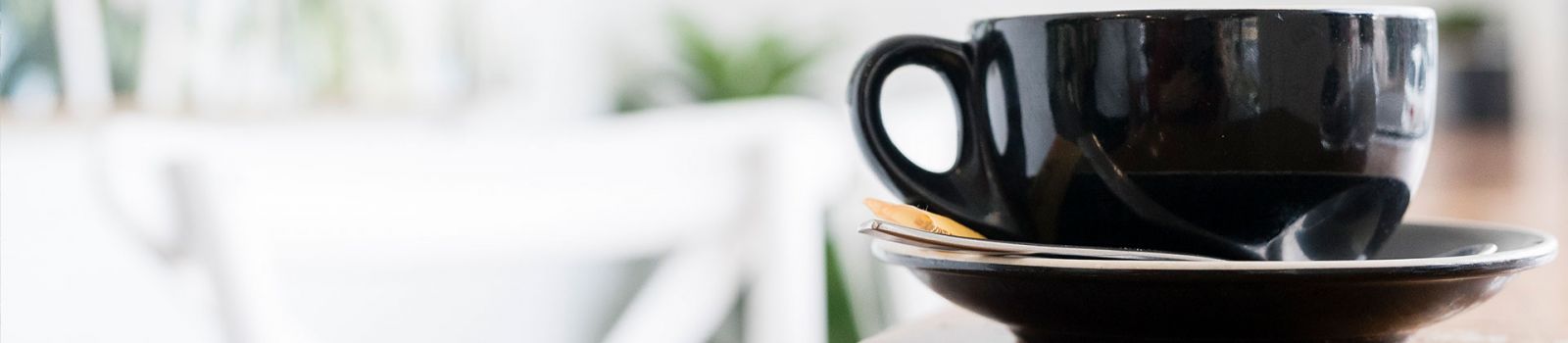 Image of a cup of coffee sitting on a bench in a cafe banner image