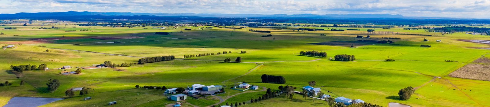 Photograph looking out over paddocks and a river banner image