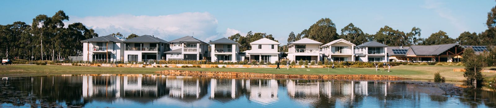 Photograph of a row of newly developed houses over looking a lake banner image