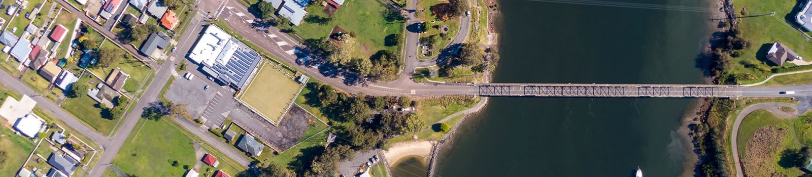 Aerial photograph looking down on a river with a bridge connecting the two sides banner image