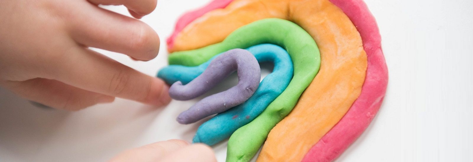 Different colour play doh rolled up forming a rainbow banner image