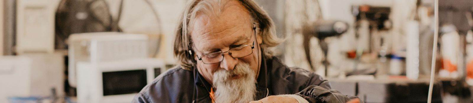 Image of an older man doing wood work and smiling  banner image