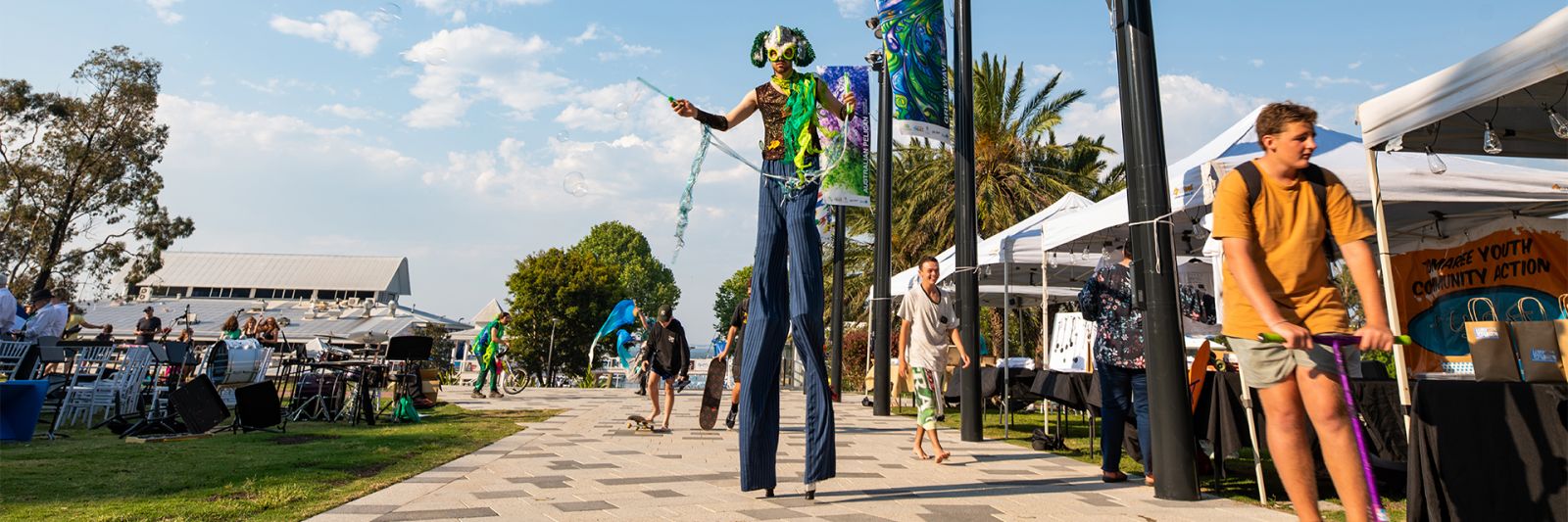 Stilt walker in costume blowing bubbles banner image