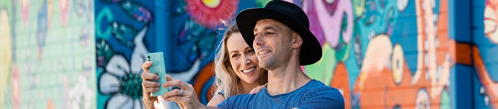 Photo of two people standing in front of art taking a photo of themselves banner image