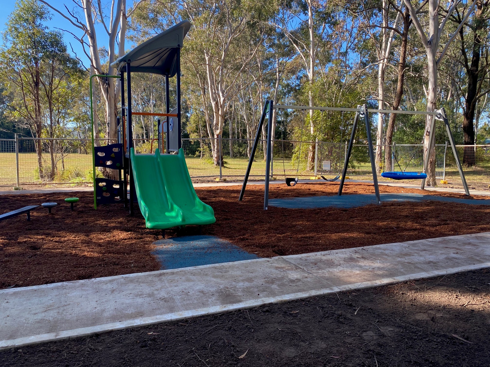 playground with 2 green slides and 2 blue swings