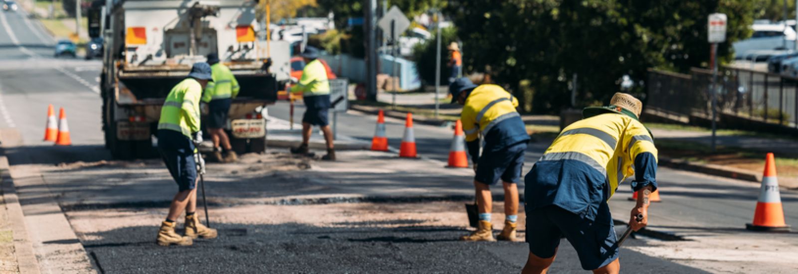 Men working on a road, patching it banner image