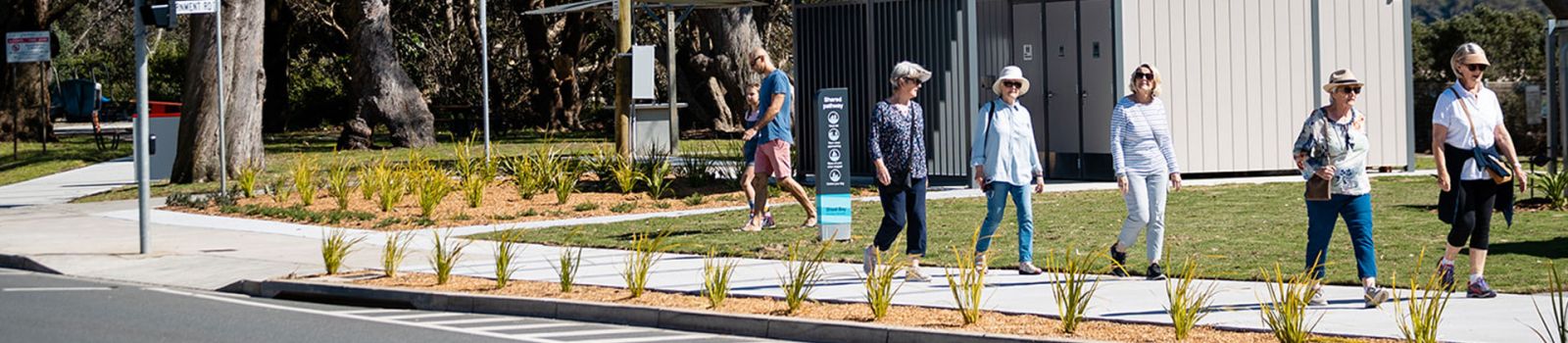 People walking along a pathway near a beach  banner image