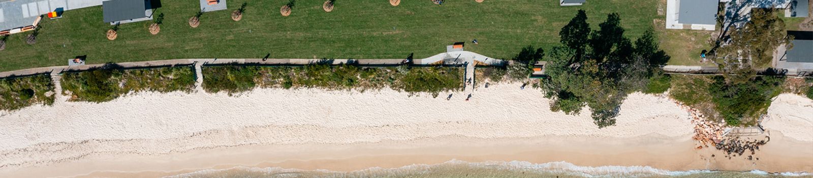 Aerial photograph over looking a shoreline with a beach and houses. banner image